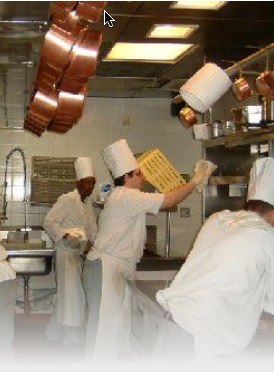 Photo of three kitchen workers cleaning up a commercial kitchen area.