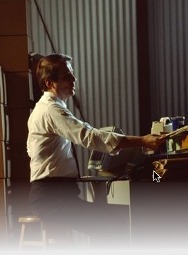 Photo of a male in a warehouse sitting doing paperwork.