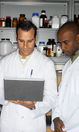 two scientists examining material on an electronic device