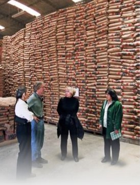 Photo of four people in a warehouse that is filled to the ceiling with packaged goods.