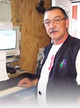 Photo of a male warehouse worker standing in front of a computer station.